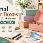 Pastel-colored corrugated mailer boxes with color swatches and measuring tape on a small business packaging desk.